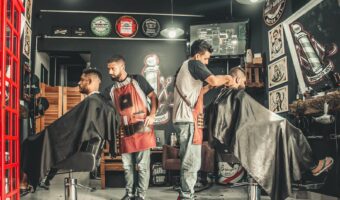 A bustling barbershop with two men getting haircuts, showcasing a vibrant barber environment.