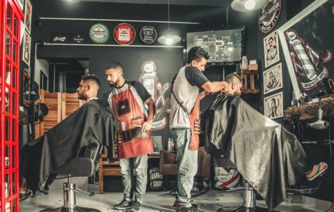 A bustling barbershop with two men getting haircuts, showcasing a vibrant barber environment.