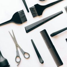 Photo by Nataliya Vaitkevich Flat lay of essential hairdressing tools including brushes, combs, and scissors on white background.